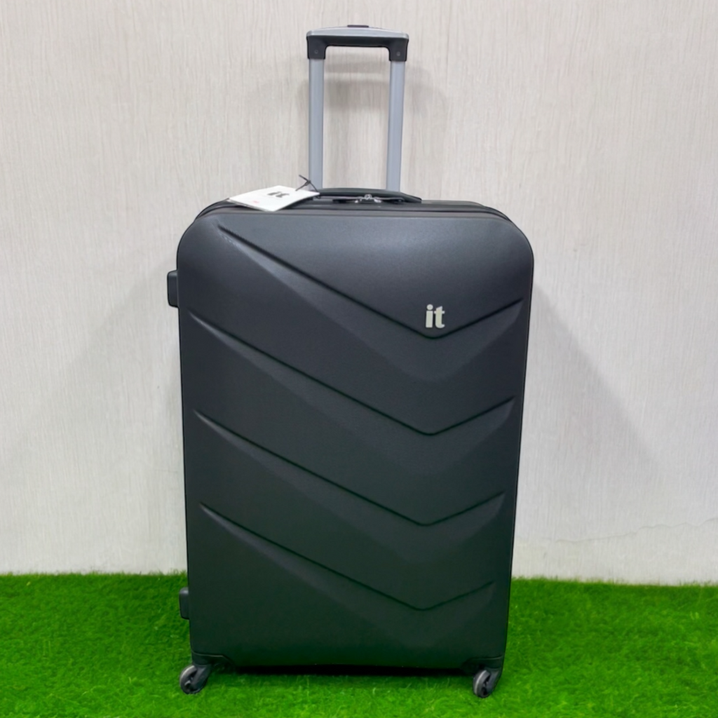 a black IT Luggage Chevron hard-shell suitcase featuring a textured finish and multi-directional wheels.