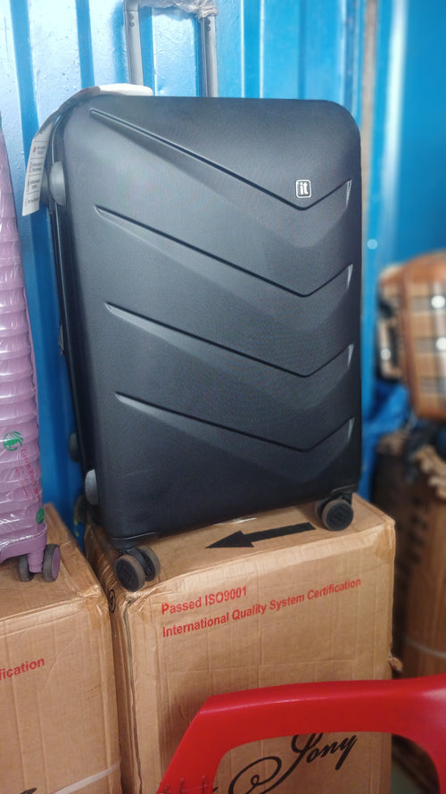 a black IT Luggage Chevron hard-shell suitcase featuring a textured finish and multi-directional wheels.