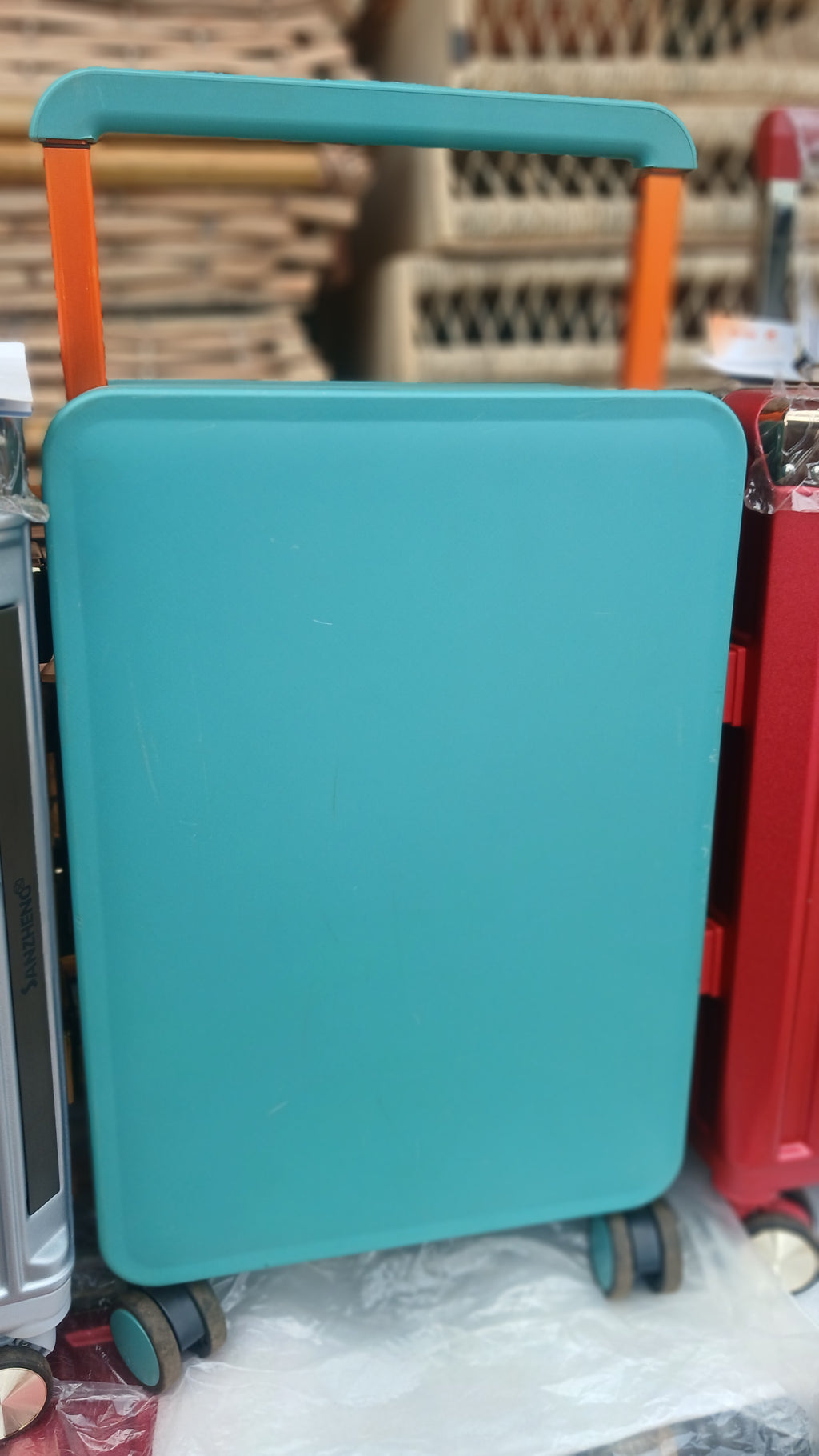 Sanzheng suitcase with a teal hard shell and orange trolley handle.
