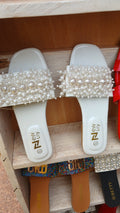 white ladies' sandal with a decorative pearl-embellished strap.